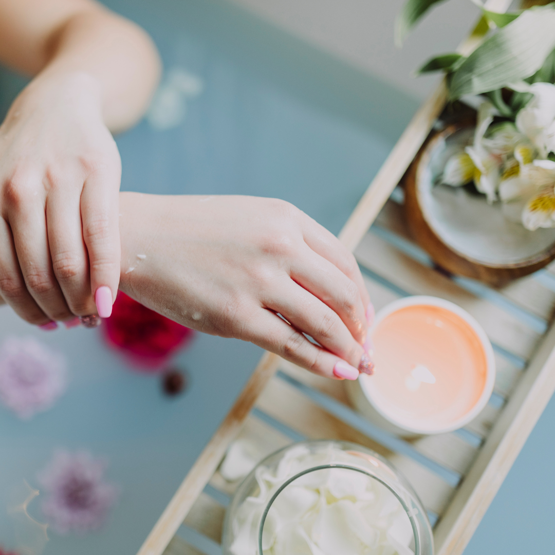 Hand scooping a botanical sugar body scrub before gentle exfoliation for smoother, softer skin.